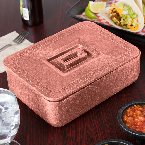 A pink metal HS Inc. multi-purpose container with a lid on a table with food.