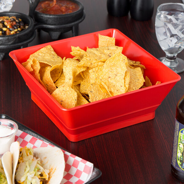 A red container with chips on a table in a Mexican restaurant.