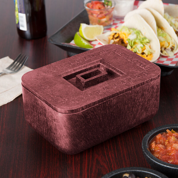 A rectangular raspberry container with a lid on a table with food.