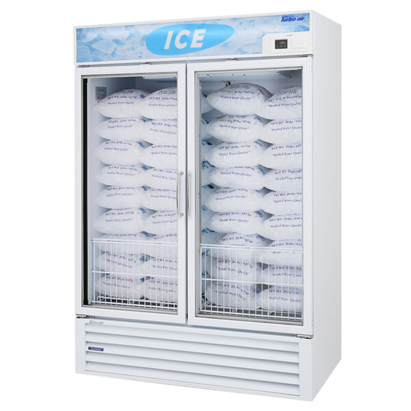 A Turbo Air white glass door freezer filled with bags of ice.