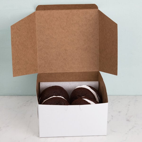 A white bakery box filled with chocolate cookies with the lid open.