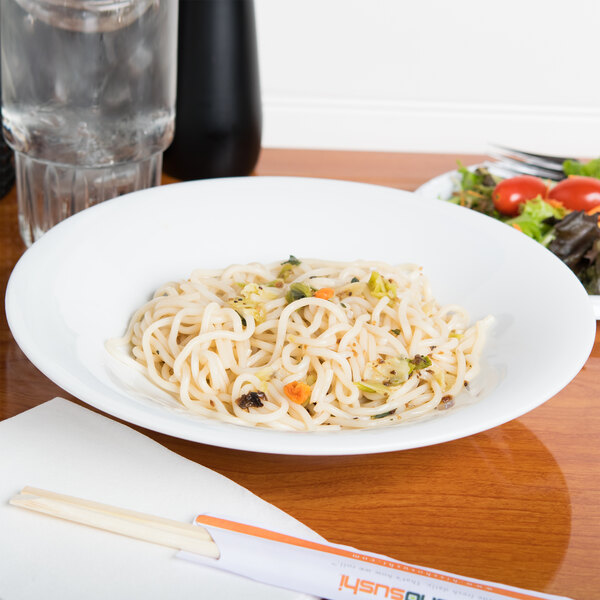 A CAC porcelain bowl filled with noodles and vegetables on a table.
