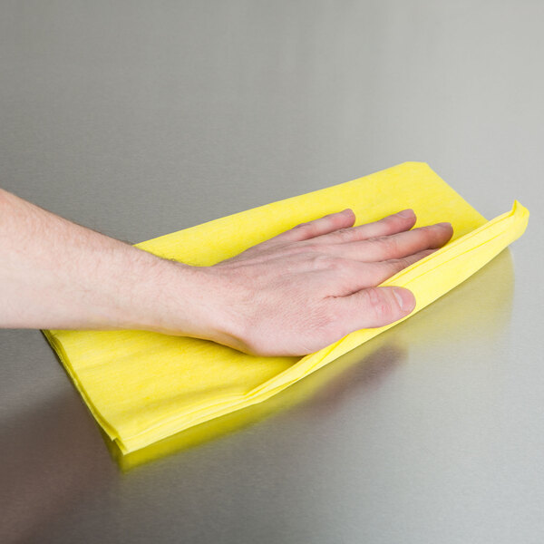 A person using a yellow Chicopee light-duty dusting cloth.