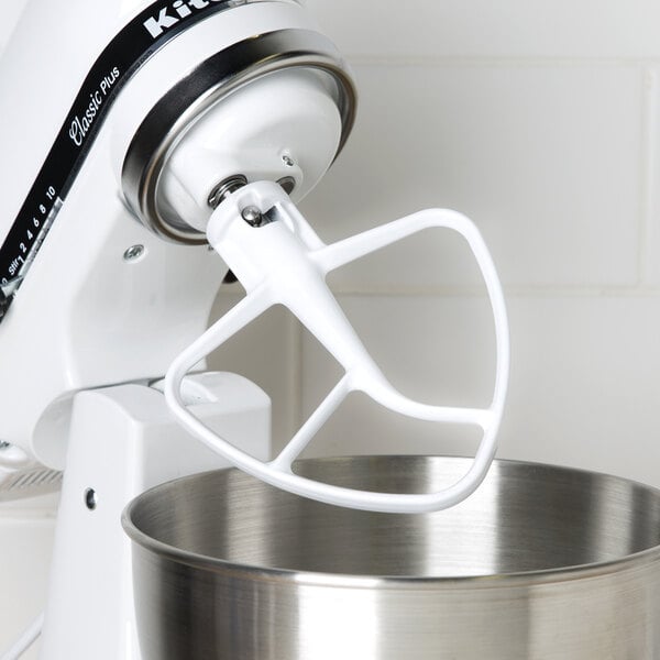 A white KitchenAid stand mixer with a bowl and a coated flat beater attached.