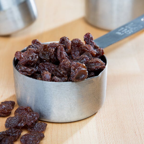A measuring cup full of California Select Raisins on a table.