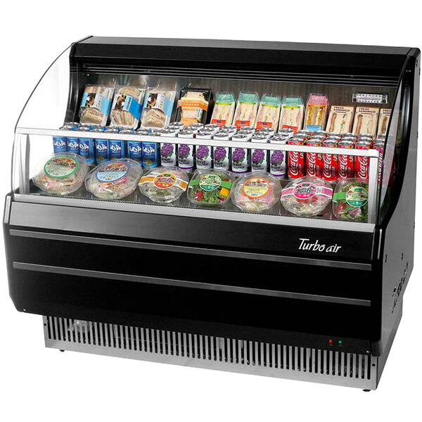 A black Turbo Air horizontal air curtain display case with food inside, including a plastic container of salad with a green label.