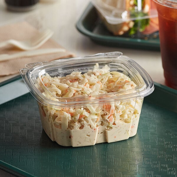 A Dart plastic container of coleslaw on a tray.