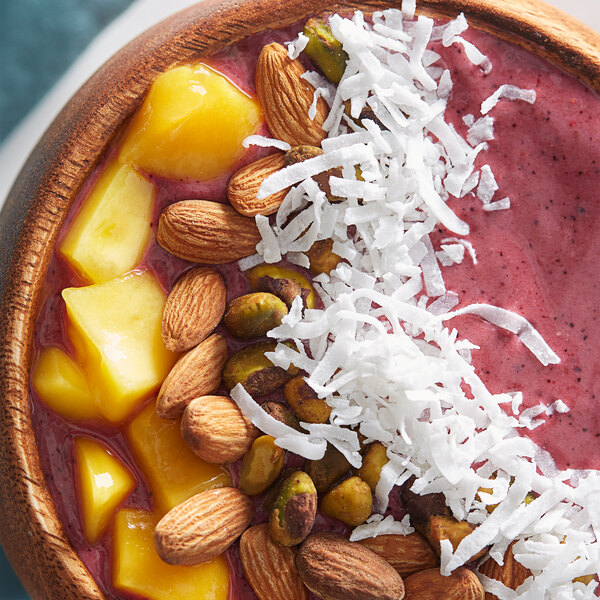 A bowl of fruit and nuts including yellow Sweet Coconut Flakes.