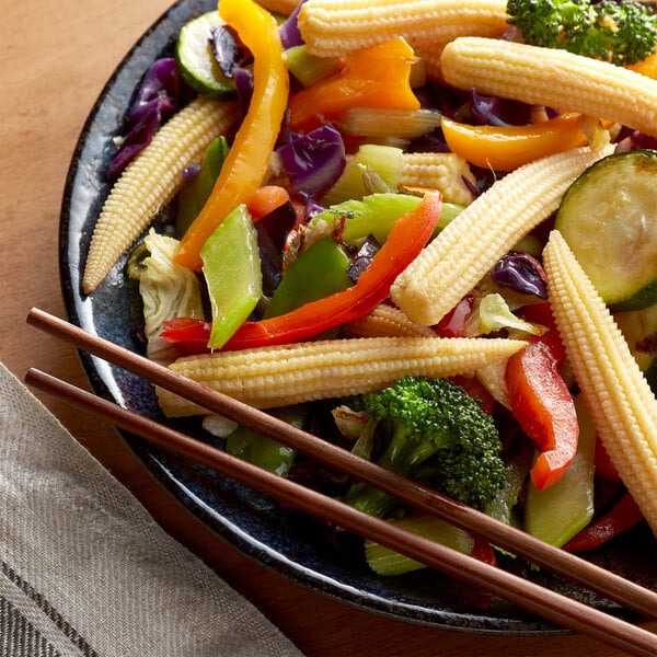 A plate of vegetables with whole baby corn on it.