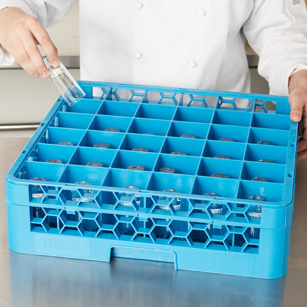 A person using a Carlisle glass rack to put a glass in a blue container.