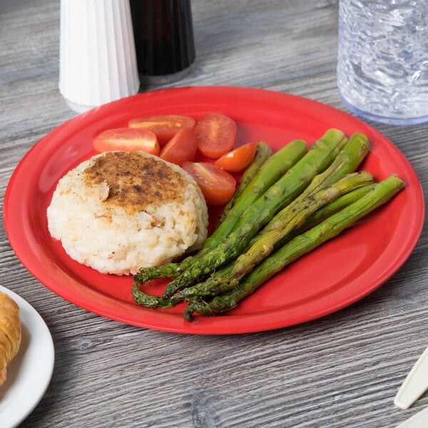 A Carlisle red melamine plate with food on a table.