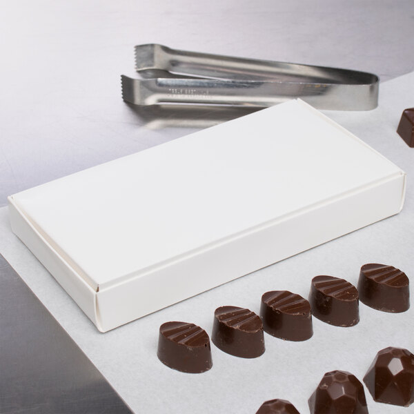 A white candy box filled with chocolates on a counter.