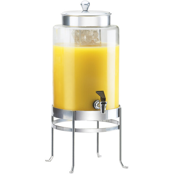 A Cal-Mil glass beverage dispenser with an ice chamber on a stand filled with orange juice.