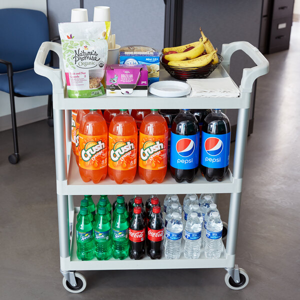 A Cambro speckled gray utility cart with shelves holding drinks and snacks.