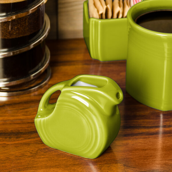A Fiesta Lemongrass mini disc creamer pitcher on a wood surface.