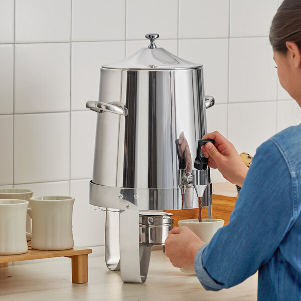 A woman using a Choice Economy Stainless Steel Coffee Chafer Urn to pour coffee.