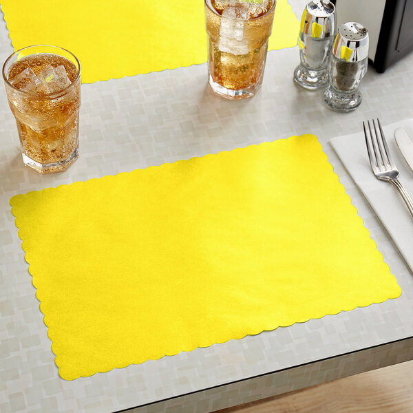A yellow scalloped edge paper placemat on a table with a glass of ice tea.