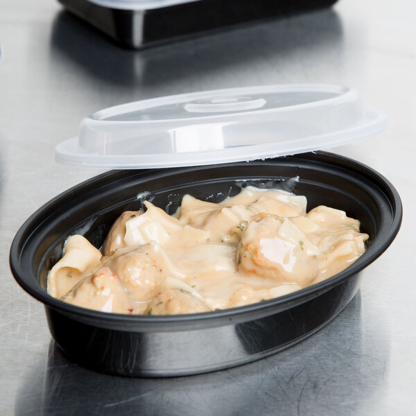 A Pactiv Newspring black oval microwavable container with food and a lid.