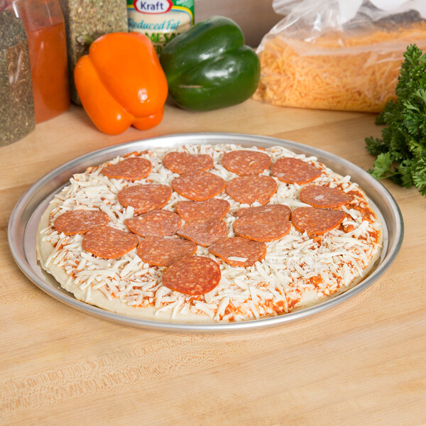 An American Metalcraft aluminum pizza pan with a pepperoni and cheese pizza on it.