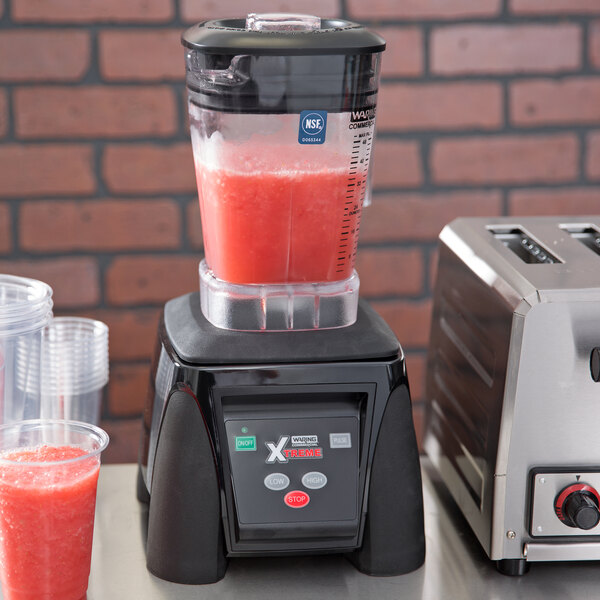 The Waring Xtreme commercial blender with a red drink in the container.