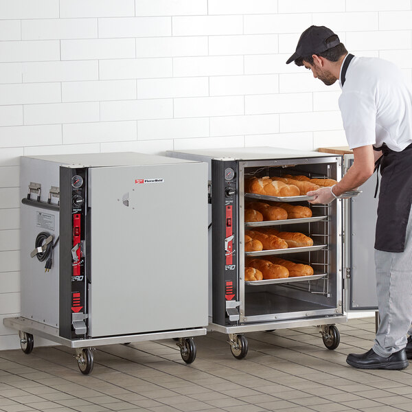 A man using a Metro heated holding cabinet to hold trays of bread.