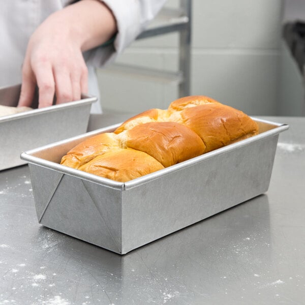 A hand preparing bread in a Chicago Metallic aluminized steel loaf pan.