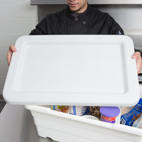 A man in a chef's uniform holding a white rectangular Winholt lid.