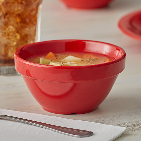 A close-up of a red bowl of soup on a table.