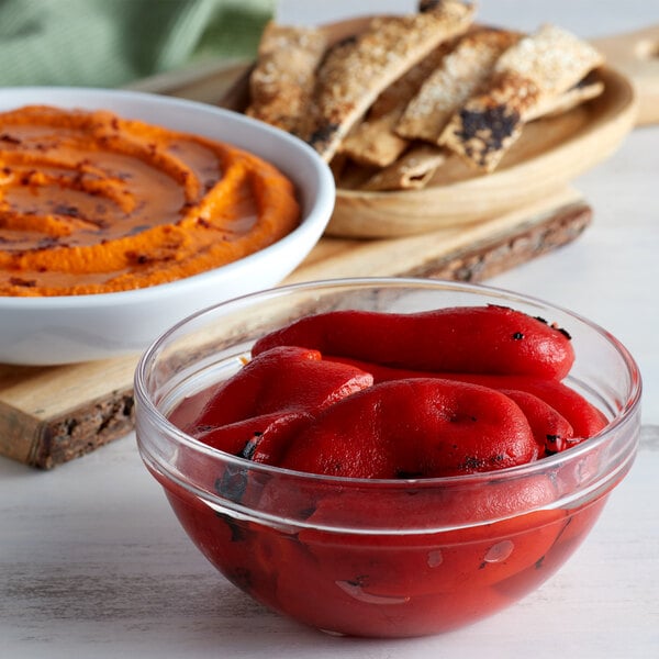 A bowl of Furmano's roasted red peppers next to a bowl of orange hummus.