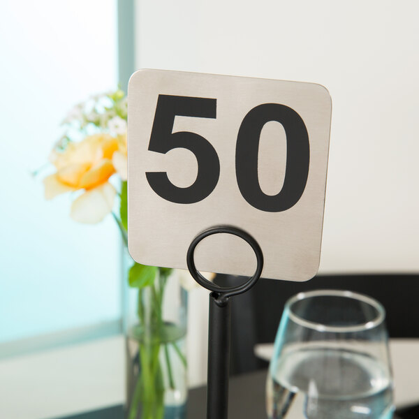 Tablecraft stainless steel table number 50 on a counter.