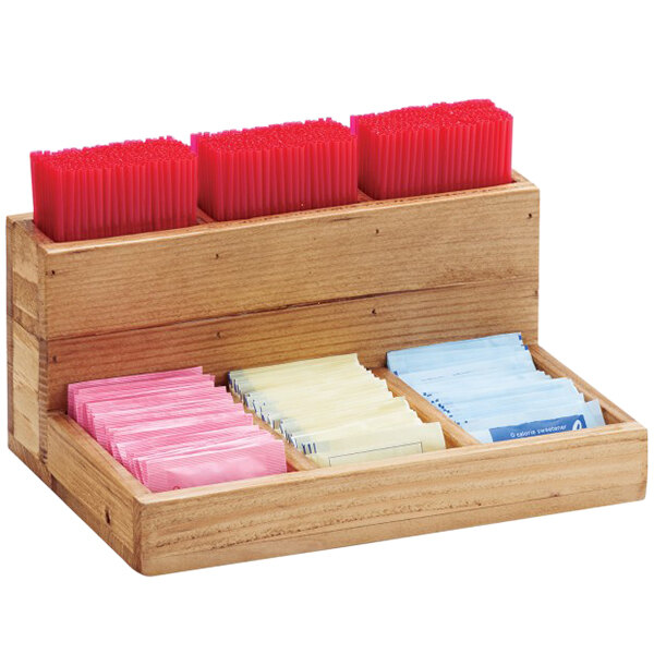 A wooden box with several compartments holding stir sticks and packets.