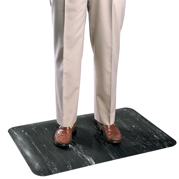 A person standing on a black Cactus Mat with marbled black pants.