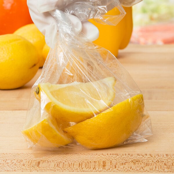 A hand in a white glove holding a plastic bag of lemon wedges.