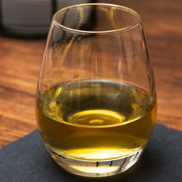 A Libbey spirits glass filled with yellow liquid on a coaster.