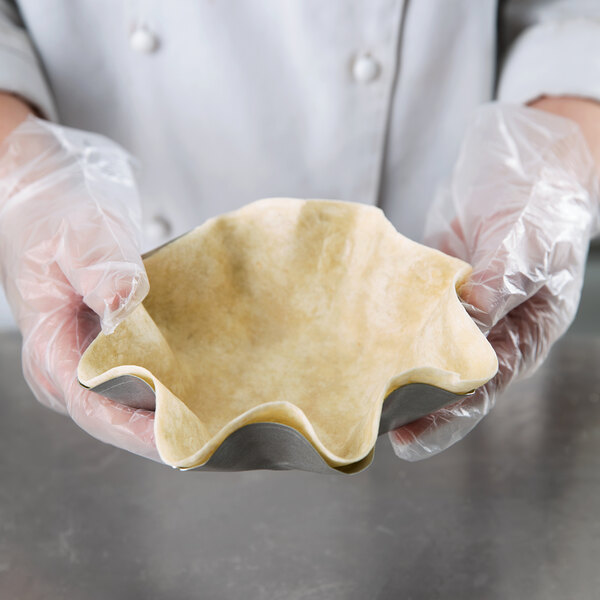 A person in gloves holding a pastry bowl of dough.