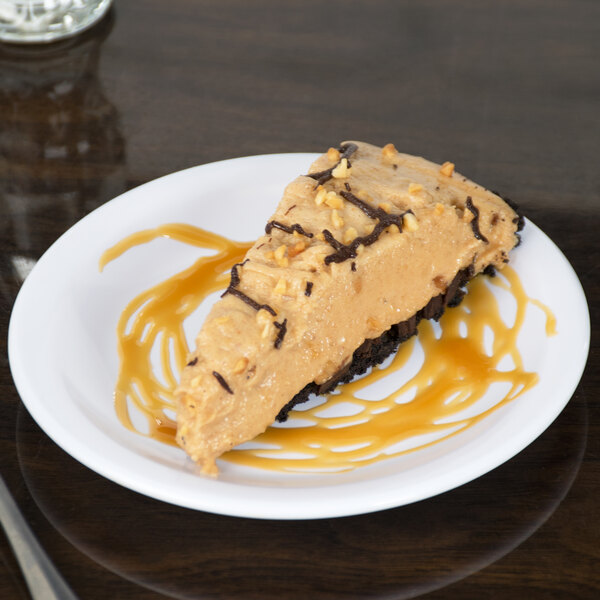 A slice of pie with peanut butter and chocolate topping on a white Carlisle melamine plate.