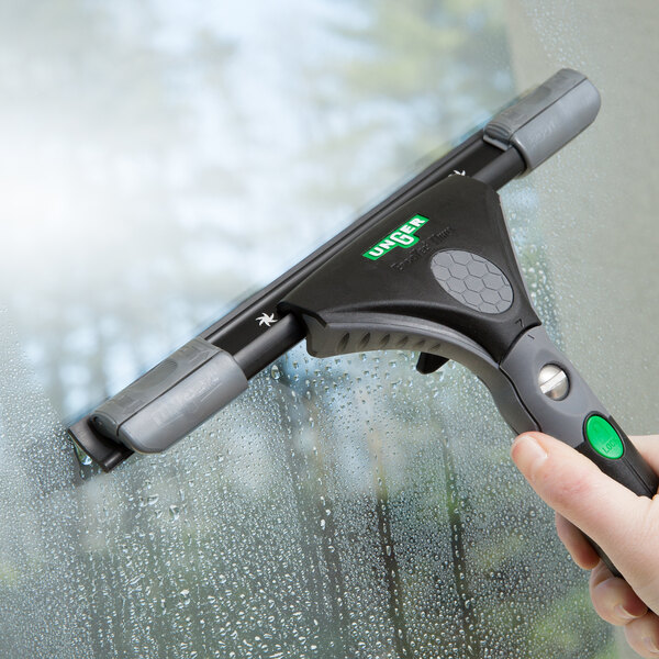 A hand using a Unger ErgoTec Ninja squeegee to clean a window.