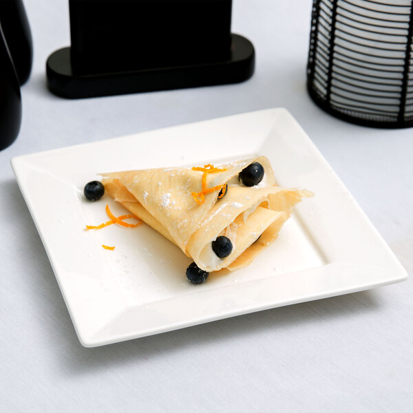 An Arcoroc porcelain plate with a crepe and blueberries on it.