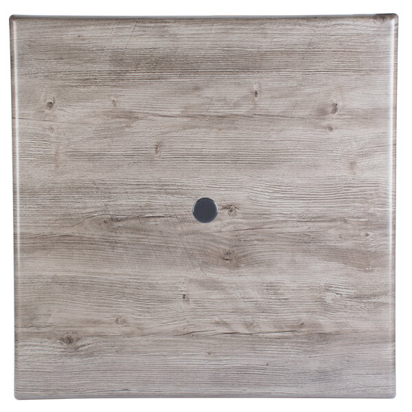 A wood square table top with a black circle in the middle.