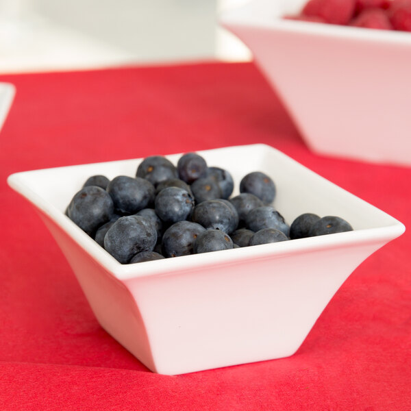 A square Arcoroc flared bowl filled with blueberries and raspberries.