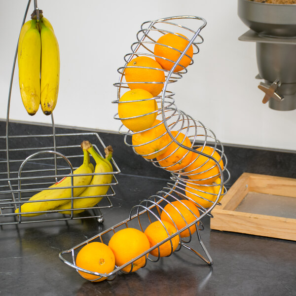 A Tablecraft chrome metal fruit basket filled with oranges.