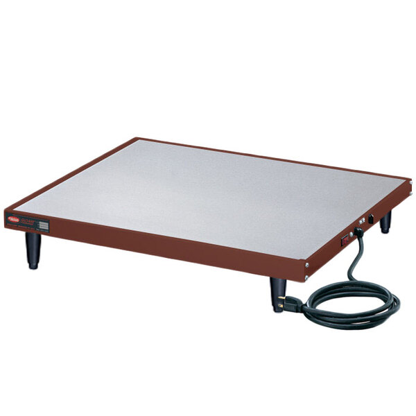 A white rectangular table with a brown border and a copper rectangular heating shelf on it.