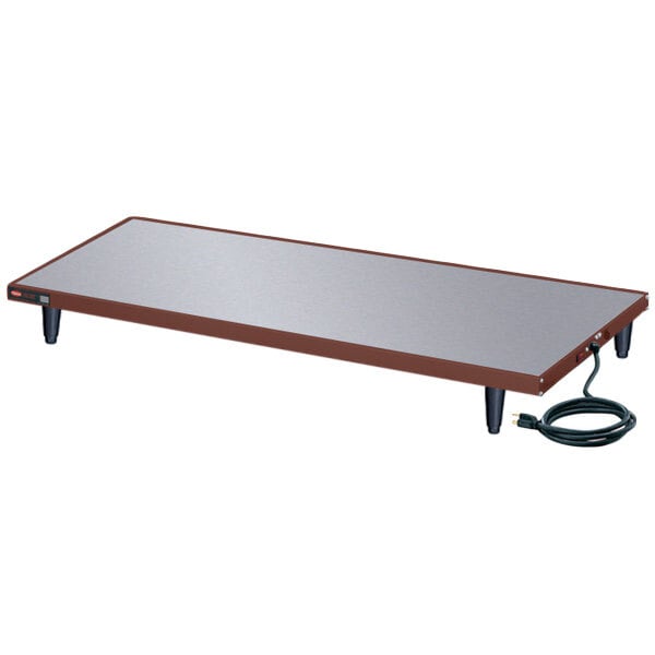 A rectangular brown and copper Hatco heated shelf on a table with a cord.