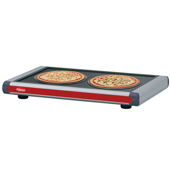 A Hatco heated shelf with pizza pans holding pizzas on a table.