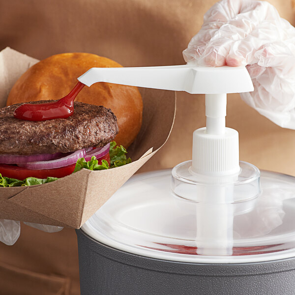 A person holding a burger with ketchup on top of it using an Economy Pump.