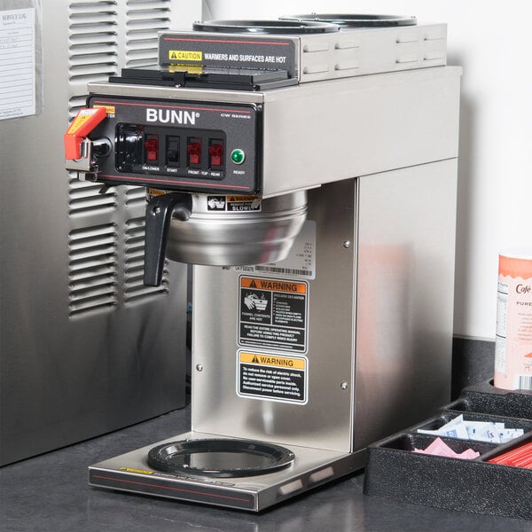 A Bunn commercial automatic coffee maker on a counter next to a tray of condiments.
