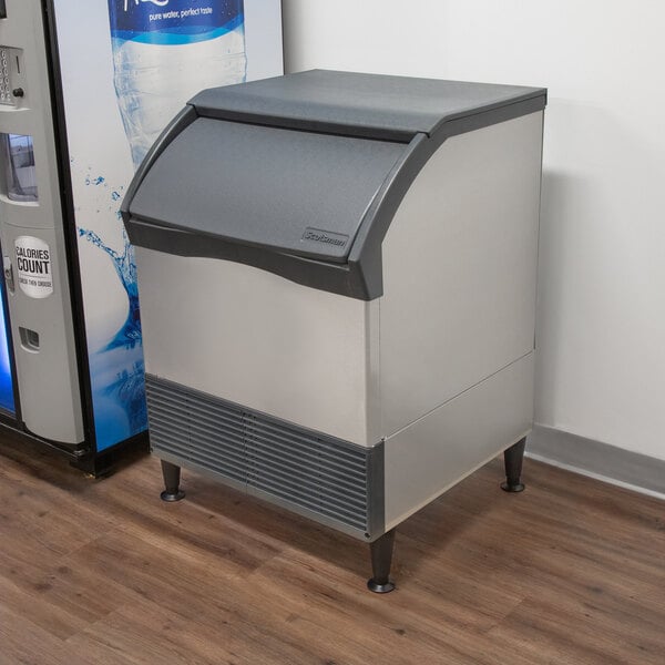 A Scotsman undercounter ice machine on a counter next to a container.