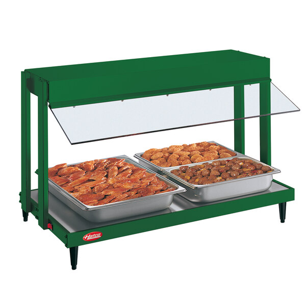 A Hatco Hunter Green mini-merchandising warmer with two trays of food on a buffet table.