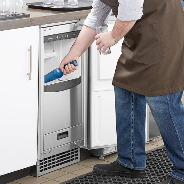 A man in a blue apron cleaning a Scotsman undercounter ice machine.