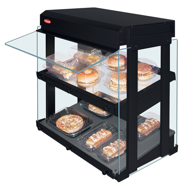 A Hatco mini-merchandising warmer with slanted glass shelves displaying food.